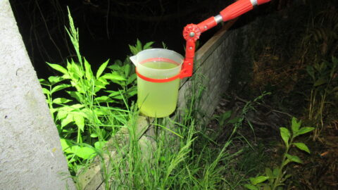 fotografia wykonana w porze nocnej na której widać urządzenie z pojemnikiem do poboru wody. Woda kolorze zielonym